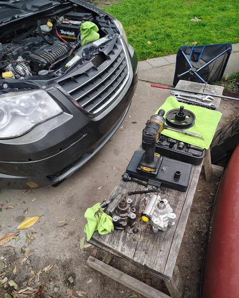Mobile mechanic tools and replacement parts beside a vehicle in a driveway